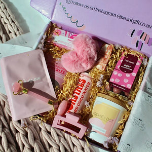 Beaut Box with Pamper & Self-Care Products for Women including a soap, chocolate bag, candle, hair claw, keychain, face mask, face roller, coconut water, bag, and rocky road treat