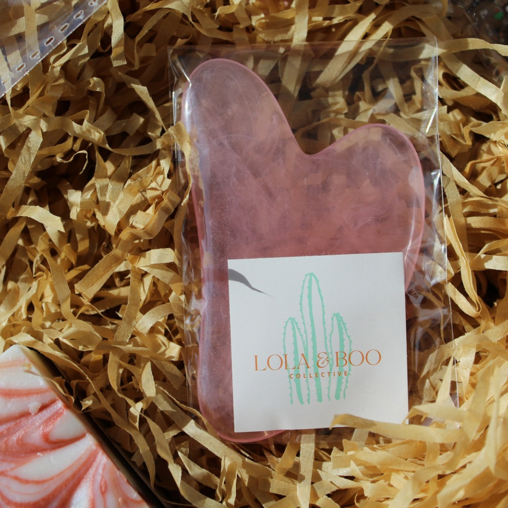 Pink resin Gua Sha massage tool for face and body, designed to boost blood circulation and enhance self-care.