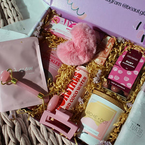 Beaut Box with Pamper & Self-Care Products for Women including a soap, chocolate bag, candle, hair claw, keychain, face mask, face roller, coconut water, bag, and rocky road treat