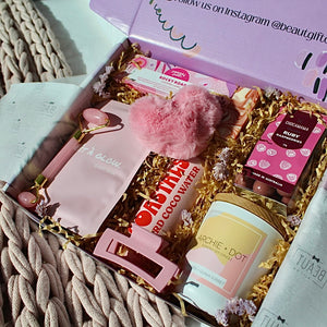 Beaut Box with Pamper & Self-Care Products for Women including a soap, chocolate bag, candle, hair claw, keychain, face mask, face roller, coconut water, bag, and rocky road treat