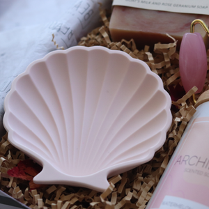 Handmade clay shell dish used as a candle holder on a bedside table