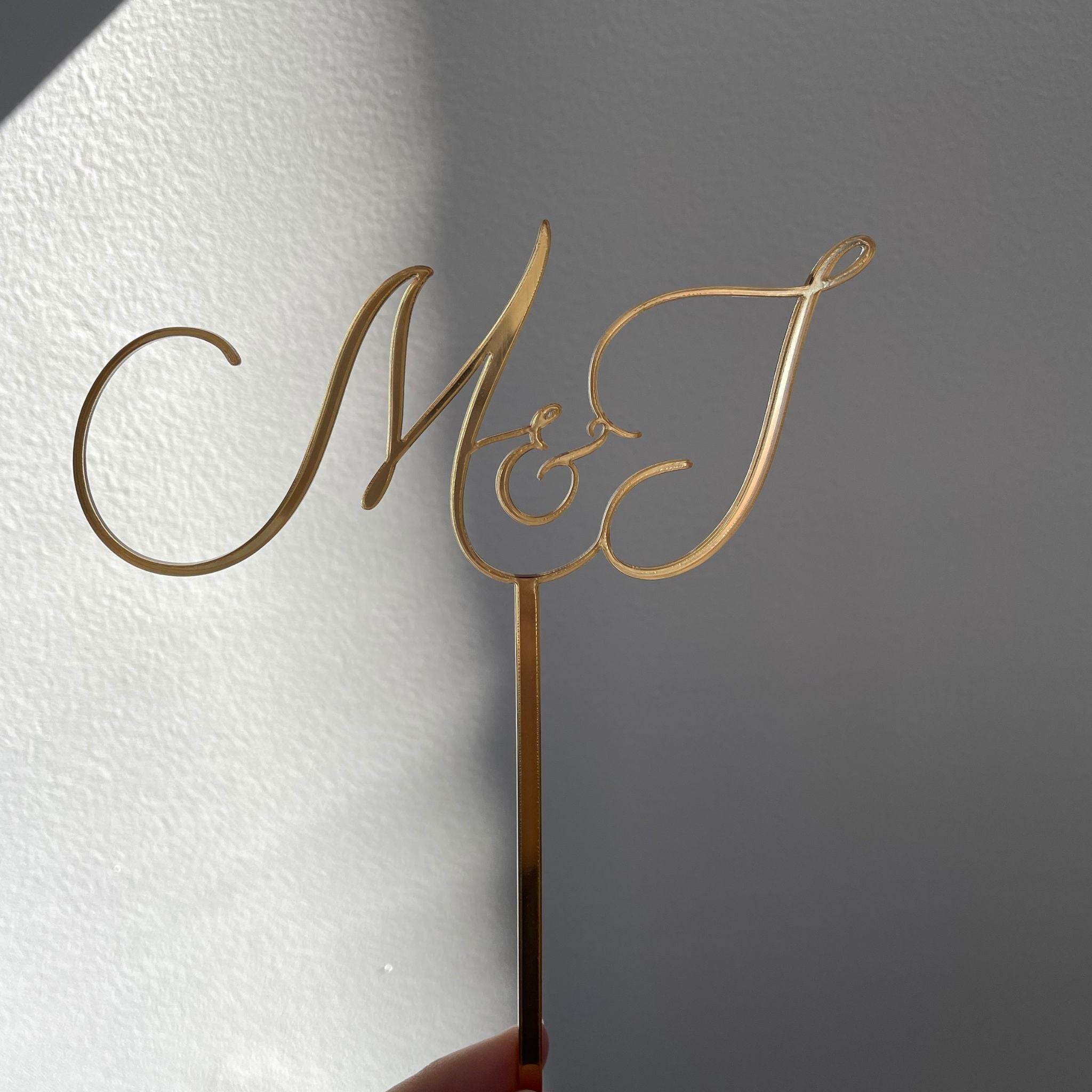 initials M&J in cursive writing as a gold cake topper custom made in sydney 