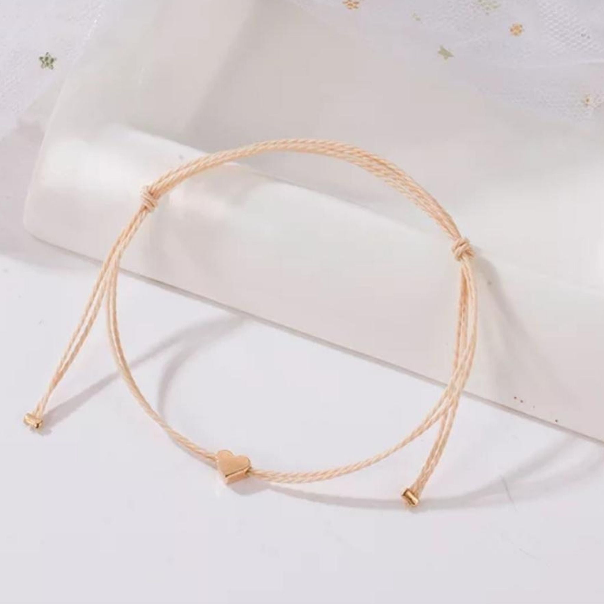 minimalist bracelet with rose gold heart and cream thread